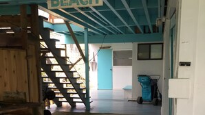 Een houten trap die leidt naar een kamer met een bord waarop staat 'DEZE KANT OP NAAR HET STRAND'.