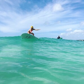 Una persona fa surf nell'oceano sotto un cielo sereno.