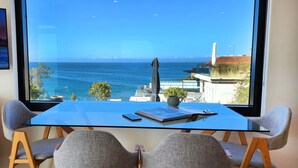 Een moderne kamer met een groot raam met uitzicht op zee en verre bergen.