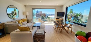A modern living room with a sofa, coffee table, and dining area.