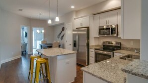 A modern kitchen with granite countertops, stainless steel appliances, and pendant lighting. - July Fun! Happy & Chill in West Nashville! (Nashville)