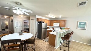 Una cocina moderna con una isla central, armarios de madera y un comedor con una mesa redonda y sillas.