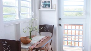 Een eetruimte met een tafel, stoelen, een vaas met bloemen en een deur naar een balkon.
