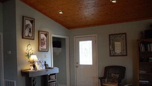 A cozy living room with wooden flooring, a fireplace, a dog, a chair, and a bookshelf. - Welcome to Tranquility (Ivanhoe)