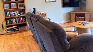 A living room with a wooden ceiling, a bookshelf, a television, and a sofa. - Welcome to Tranquility (Ivanhoe)