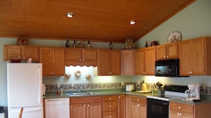 A kitchen with wooden cabinets, a refrigerator, a microwave, a dishwasher, and a coffee maker. - Welcome to Tranquility (Ivanhoe)