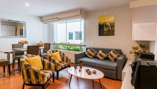 A modern living room with a sofa, two armchairs, a coffee table, and a dining area with a table and chairs. - Modern And Safe Miraflores Apartment (Miraflores)