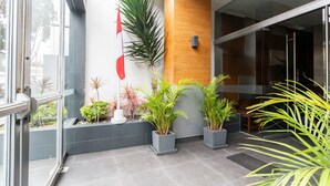 A modern lobby with a glass door, potted plants, and a wooden accent wall. - Modern And Safe Miraflores Apartment (Miraflores)