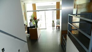 A reception area with a receptionist desk, a staircase, and a plant. - Modern And Safe Miraflores Apartment (Miraflores)