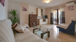 A living room with a glass coffee table, a sofa, a cabinet, and a TV. - Cozy apartment only 500m from the beach (Štinjan)