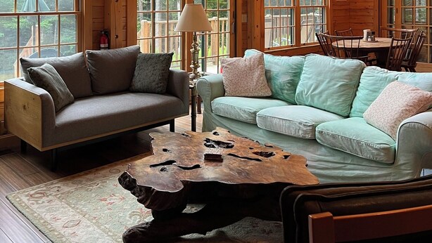 A spacious cabin with large windows, a wooden ceiling, a dining area, and a cozy seating arrangement.