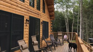 A wooden cabin with a deck, large windows, and outdoor seating.