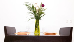 Een eettafel met twee stoelen, een vaas met bloemen en twee lege wijnglazen.