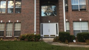 Un edificio de ladrillo de dos pisos con una entrada central, ventanas grandes y una puerta de garaje.