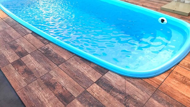 En rektangulär swimmingpool med blått kakel på insidan, omgiven av ett trädäck.