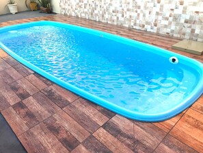 Une piscine rectangulaire à l’intérieur bleu, entourée d’une terrasse en bois.
