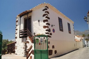 A traditional building with a staircase leading to the entrance, a green gate, and a clear sky. - Casa Rural El Olivar - La Almazara (Valle, El (Santa Lucia De Tirajana))