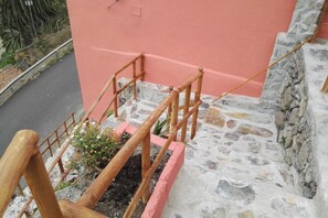 Eine Steintreppe mit einem Holzgeländer und einer rosafarbenen Wand.