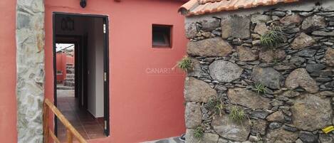 A red building with a stone wall and a tiled roof.