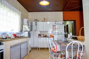 Una cocina compacta con armarios blancos, una mesa de comedor con sillas y un refrigerador.