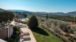 Une propriété résidentielle dotée d’une piscine, d’une pelouse bien entretenue et offrant une vue sur des collines lointaines.