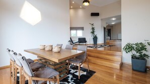 Un espace de repas moderne avec une table et des chaises en bois, un tapis noir et blanc et un escalier menant à une autre pièce.