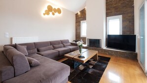 Un salon moderne avec un canapé d’angle, une table basse, un téléviseur à écran plat et une cheminée.