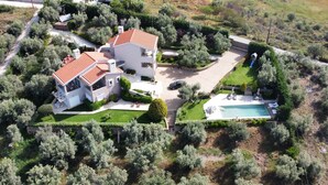 Une maison à deux étages avec une piscine, entourée d’une végétation luxuriante.