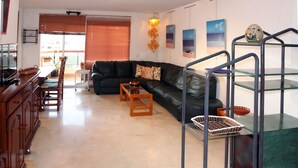 Una sala de estar moderna con un sofá de cuero negro, una mesa de centro de madera y una escalera de cristal.