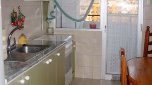 Cocina pequeña con lavabo, estufa y ventana con vistas a una zona residencial.