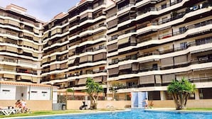 Un edificio residencial de varios pisos con una piscina en primer plano.