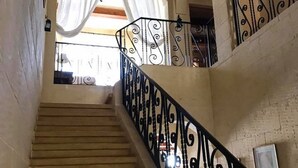 A staircase with ornate black railings leading to a balcony with white curtains. - Il- Liedna Farmhouse with private pool and beautiful views..................... (Gharb)