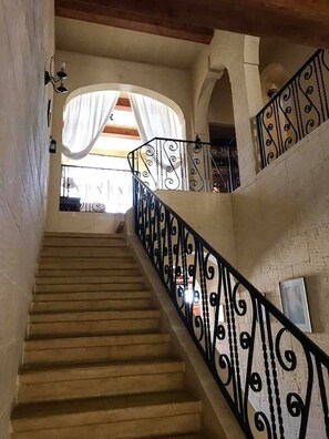 Classic staircase with a black iron railing and neutral-toned walls, leading to an upper level with a window.
