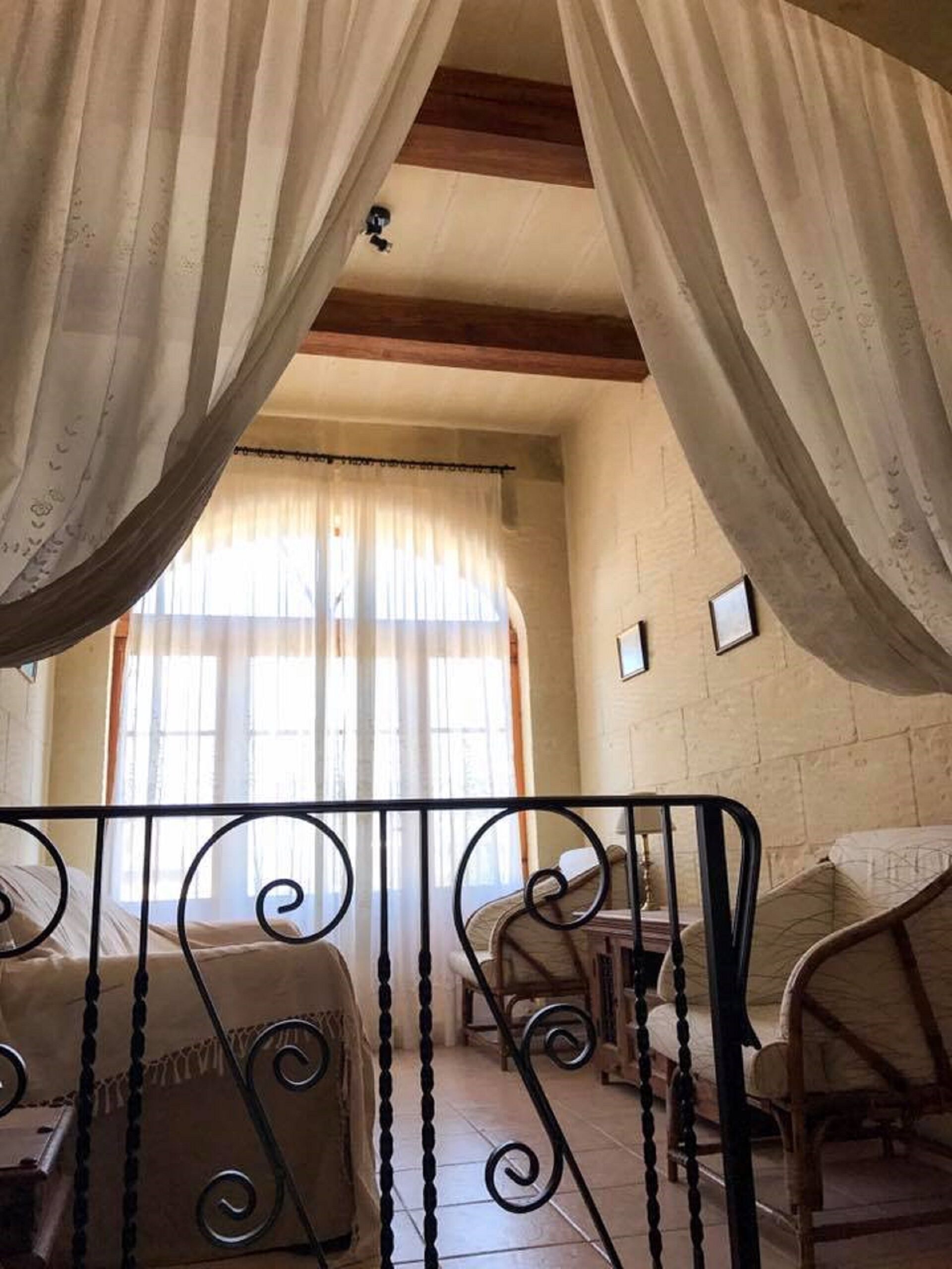 Ein Zimmer mit einem Bett, einem Sessel und einem Fenster mit Vorhängen.