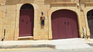 A historic building with two red doors, a small balcony, and a stone facade. - Il- Liedna Farmhouse with private pool and beautiful views..................... (Gharb)