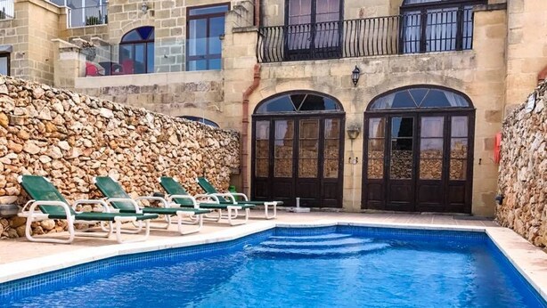 A swimming pool with lounge chairs and a stone wall. - Il- Liedna Farmhouse with private pool and beautiful views..................... (Gharb)