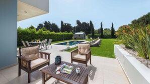 Un patio exterior con mobiliario, piscina y jardín bien cuidado.