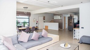 Una sala de estar moderna con sofá, comedor, cocina y una escalera que lleva a otro nivel.