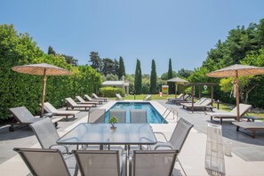Ein Poolbereich mit Liegestühlen, Sonnenschirmen und einem Tisch.