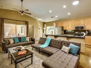 Relax in this spacious living area with a large L-shaped sofa, coffee table, and kitchenette featuring a stove and microwave.