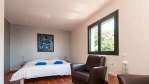A bedroom with a bed, a chair, a painting, and a window. -  Spacious family villa with pool, sea view, sauna, 10-14 persons (Sant Andreu de Llavaneres)