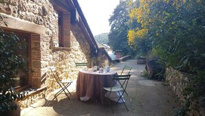 A rustic outdoor seating area with a round table and chairs, surrounded by stone walls and greenery. - The Rural Apartment - Maria's Rural House (Terán, Cabuerniga)