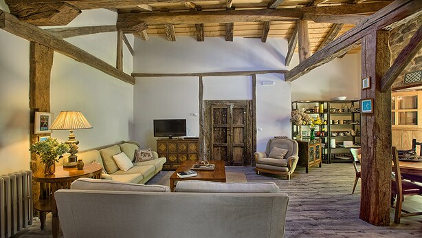 A cozy living room with a sofa, armchair, and coffee table, featuring exposed wooden beams and a rustic aesthetic. - The Rural Apartment - Maria's Rural House (Terán, Cabuerniga)