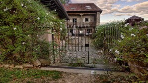 A stone house with a tiled roof, a gated entrance, and a stone pathway leading to the front door. - The Rural Apartment - Maria's Rural House (Terán, Cabuerniga)