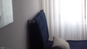 A hotel room with a bed, a chair, a table, and a window with curtains. - bed room yacopino. (Firenze)