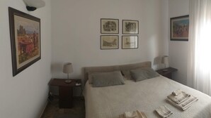 A bedroom with a bed, two bedside tables, a floor lamp, and four framed pictures on the wall. - bed room yacopino. (Firenze)
