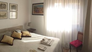 A hotel room with a bed, pillows, a chair, a lamp, and a painting on the wall. - bed room yacopino. (Firenze)