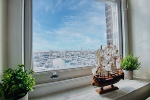 A model ship on a windowsill with a view of a marina.