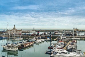 A marina with boats docked, a building with a clock tower, and a clear sky.