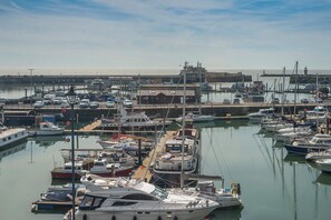 A marina with various boats docked, a pier, and a clear sky.